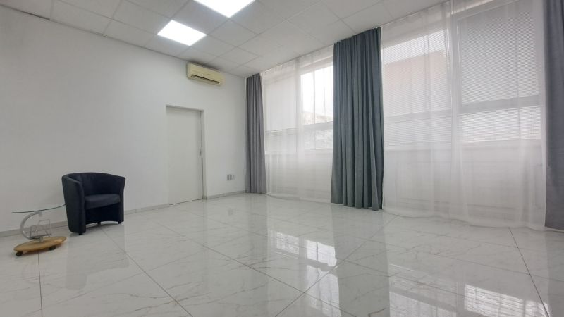 Stylish commercial spaces with white walls, ceramic flooring, an armchair, and a table.