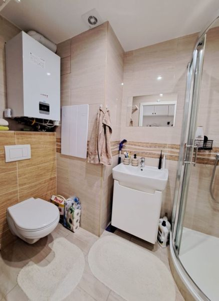 Bathroom in a 3-room apartment with a toilet and shower, light tiles.