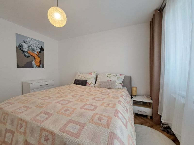 A bedroom with a light bed and nightstands in a three-room apartment with wall decorations.