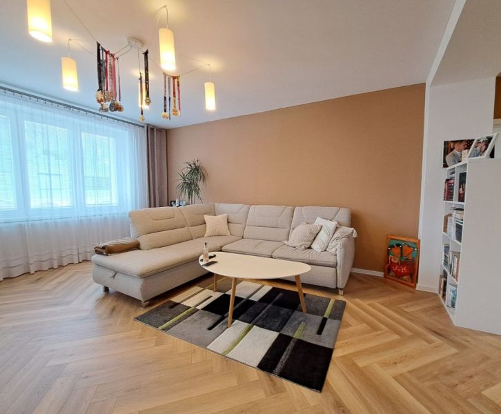 Living room in a 3-room apartment with a white sofa and a floor with a wood decor.
