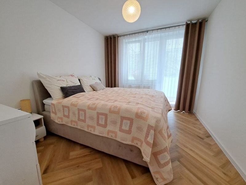 A bedroom with a double bed and a wooden decor floor in a 3-room apartment.
