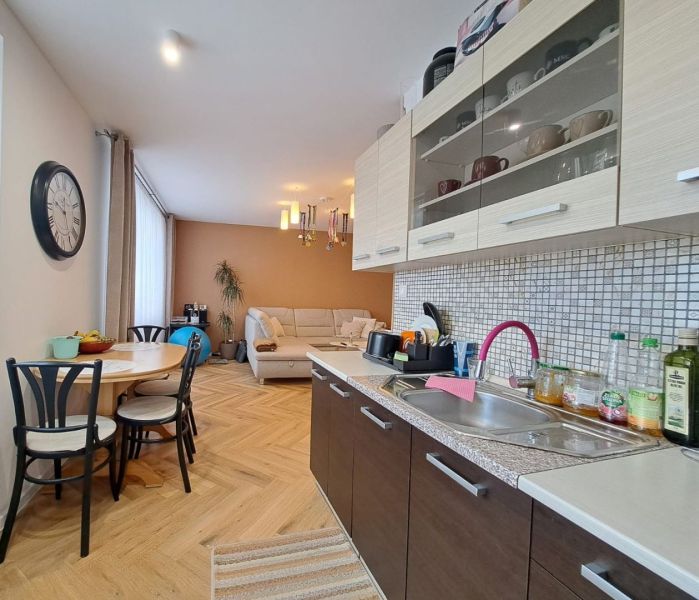 A kitchen with a dining area in a 3-room apartment, a floor with a wood decor, a sofa.