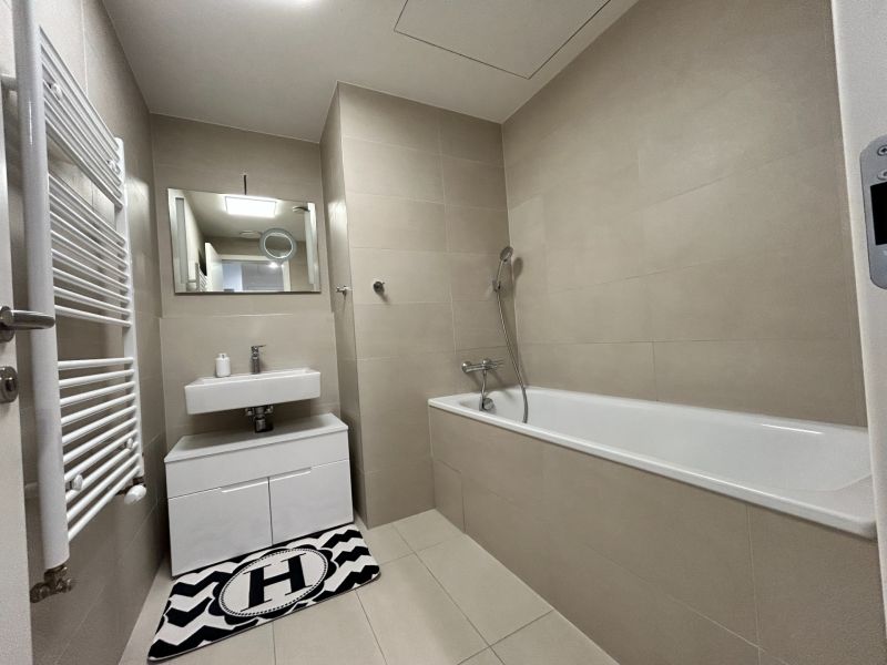 A bathroom in a 2-room apartment with a bathtub, a sink, and a wall mirror.