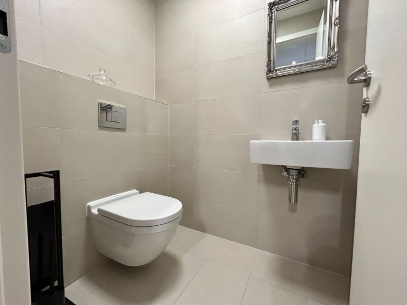 A toilet with a sink and a mirror in a 2-room apartment, beige tiles.