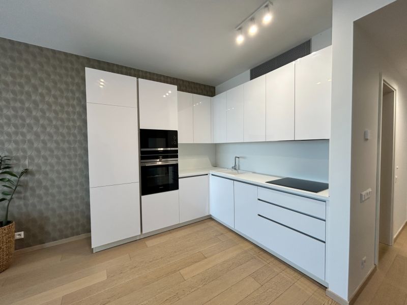 A kitchen in a 2-room apartment with a wooden decor floor and built-in appliances.