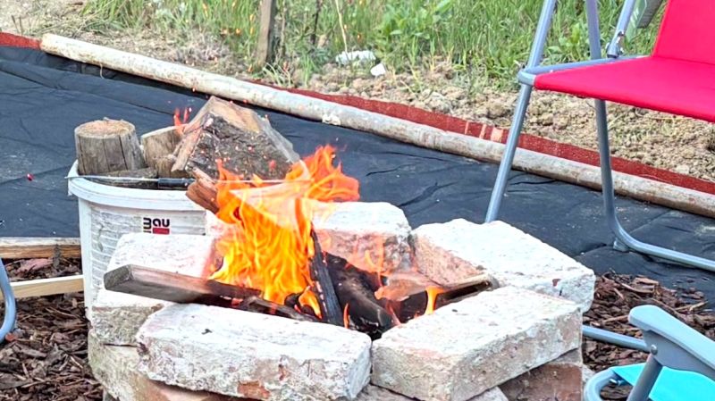 A fireplace surrounded by bricks and chairs in the garden of a family house.