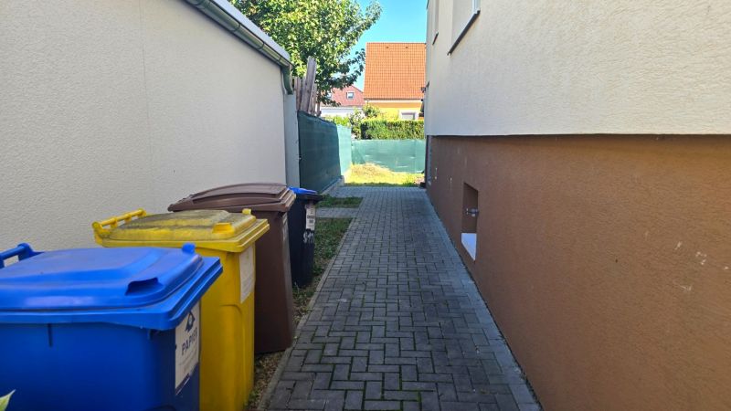 Family house on Kupeckého Street in Piešťany, waste bins, narrow sidewalk.