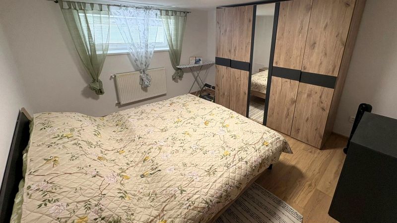 Bedroom in a family house with wood-patterned flooring, built-in wardrobe, and bed.