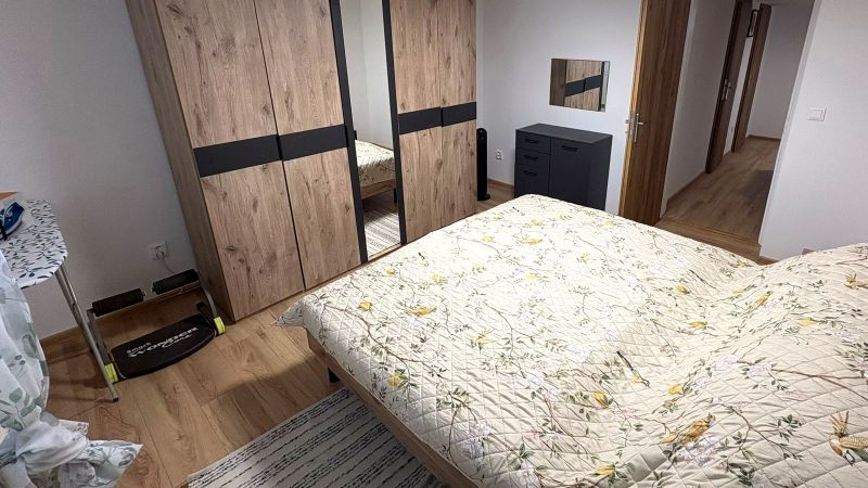 Bedroom with a bed, wardrobe, and wooden decor flooring in a family house.