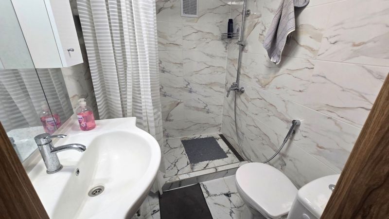 A bathroom in a family house with a sink, shower, and tiles with a marble design.