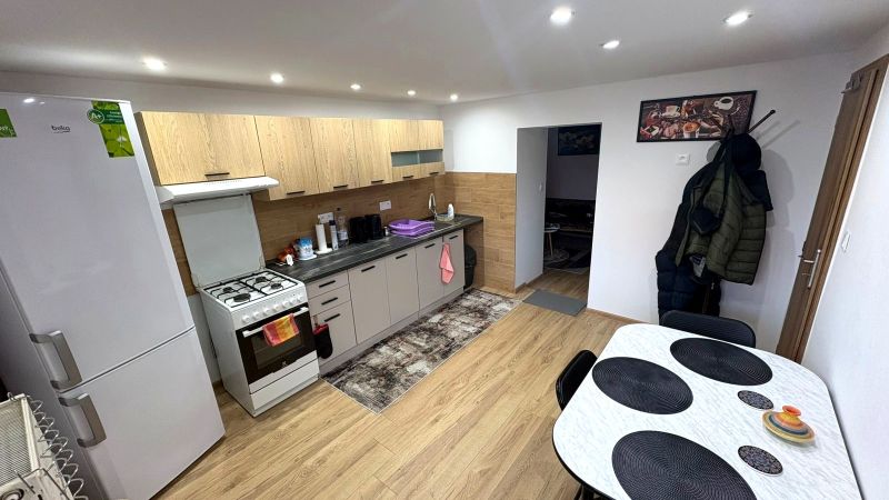 A kitchen in a family house with a wood-patterned floor, a white refrigerator, and a dining table.