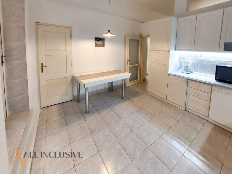 A kitchen in a 2-room apartment with white cabinets, a table, and tiles.