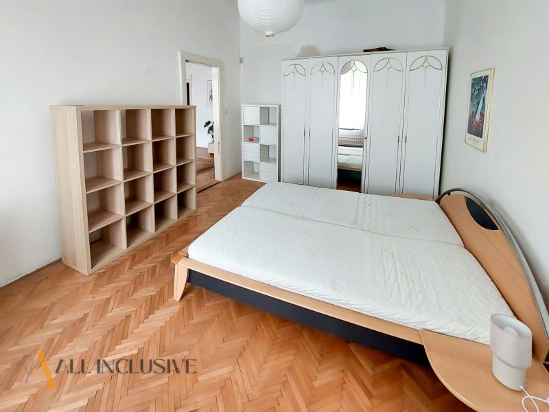 Bedroom in a 2-room apartment with wood-patterned flooring, a bed, a wardrobe, and shelves.
