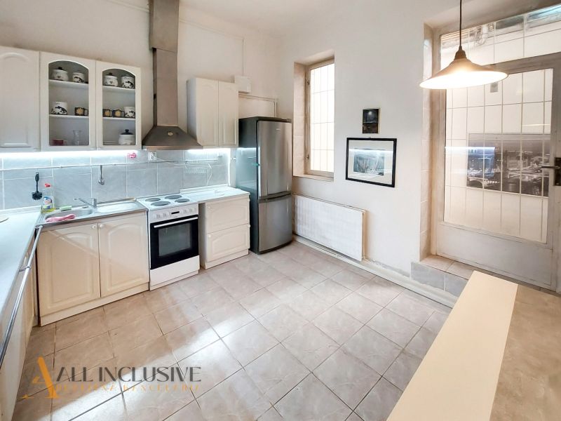 Kitchen in a 2-room apartment with white cabinets, appliances, and tiles.
