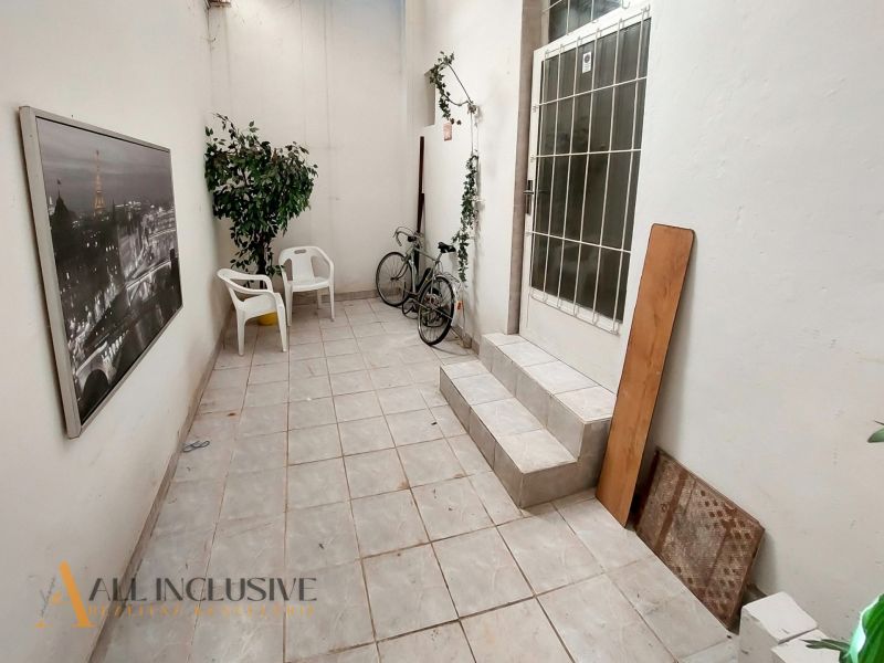 A hallway with chairs in a 2-room apartment with a bicycle and a picture of Paris.