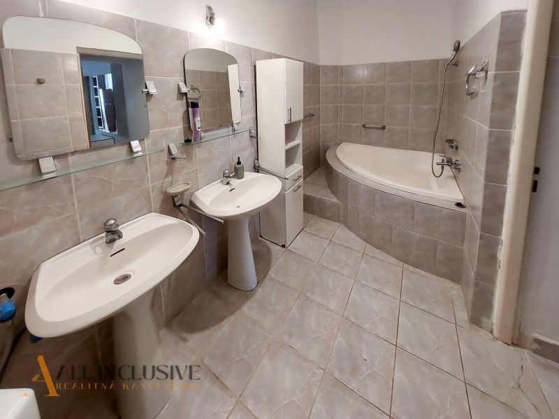 A bathroom with two sinks, a corner bathtub, and light tiles in a 2-room apartment.