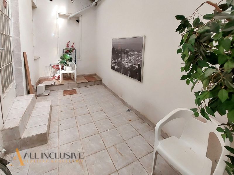 A hallway with ceramic tiles in a 2-room apartment, decorations and plastic chairs.