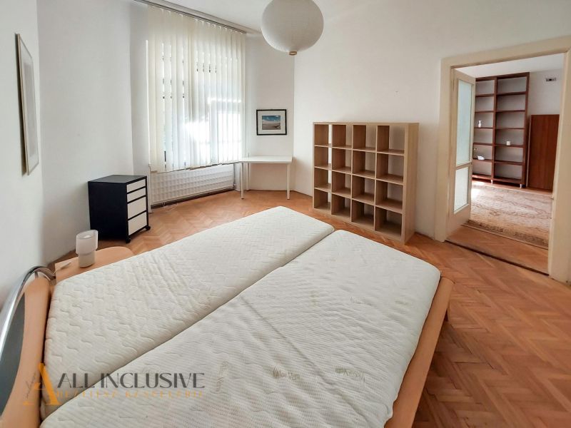 Bedroom with a built-in shelf, desk, and wood-decor flooring in a two-room apartment.