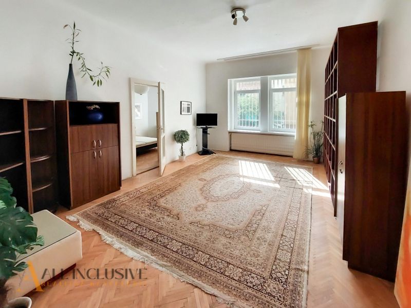 Living room in a 2-room apartment with a carpet and a floor with a wooden decor.