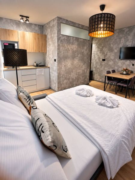 Bedroom and kitchenette in a 2-room apartment with a wooden decor floor.