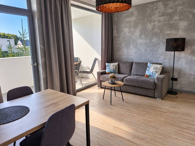 Living room in a two-room apartment with a wooden decor floor and a balcony.
