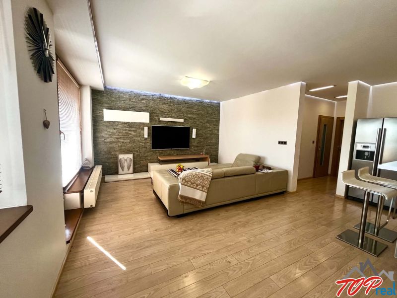 Living room in a 3-room apartment with a wooden decor floor, television, and sofa.