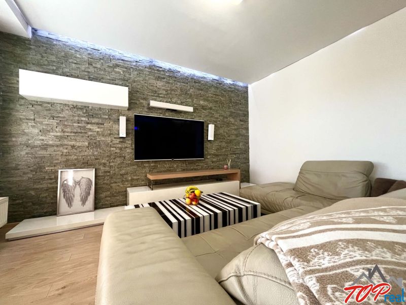 Living room in a 3-room apartment with a leather sofa and a wooden decor floor.