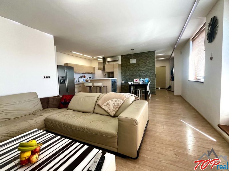 Living room of a three-room apartment with a wooden decor floor and a kitchenette.