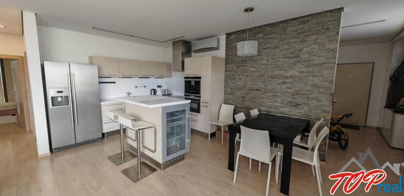 A kitchen in a 3-room apartment with a wooden decor floor and a dining table.