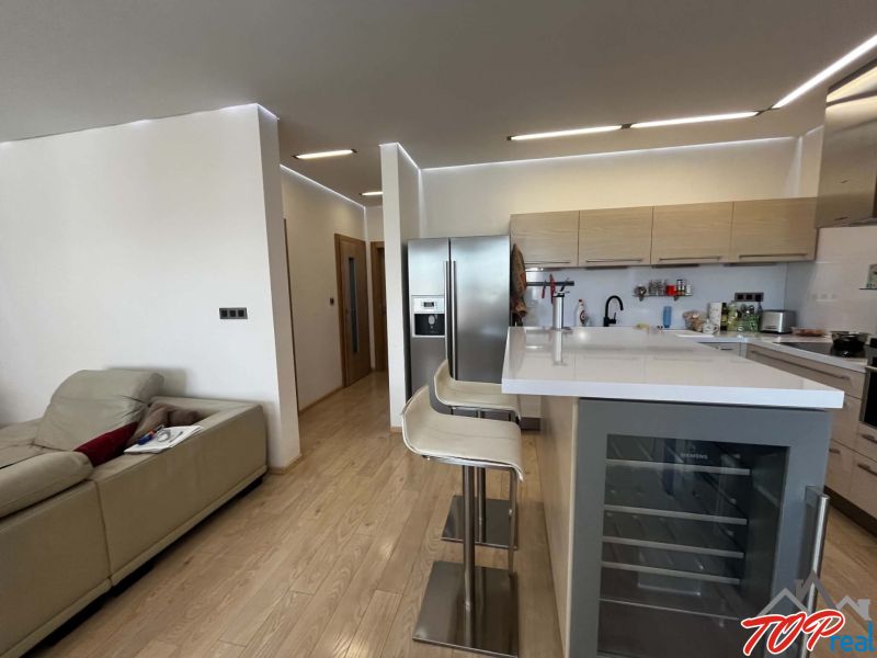 A kitchen in a 3-room apartment with a bar counter and a wooden decor floor.