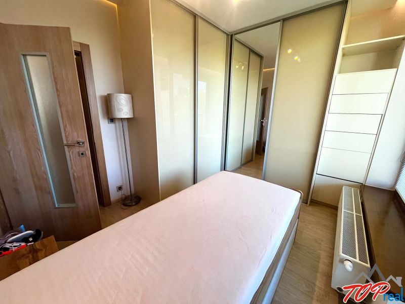 A bedroom in a 3-room apartment with a wood-patterned floor, a bed, and a built-in wardrobe.