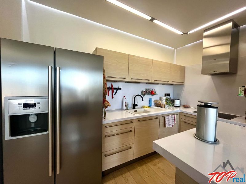 A kitchen in a 3-room apartment with a wood-patterned floor, white cabinetry, and stainless steel appliances.
