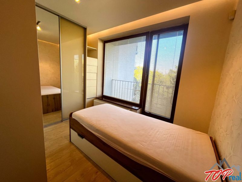 A bedroom with a wood-patterned floor and a built-in wardrobe in a 3-room apartment.