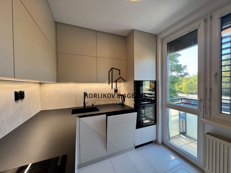A kitchen in a 3-room apartment with a modern kitchen unit, built-in appliances, and a large window.