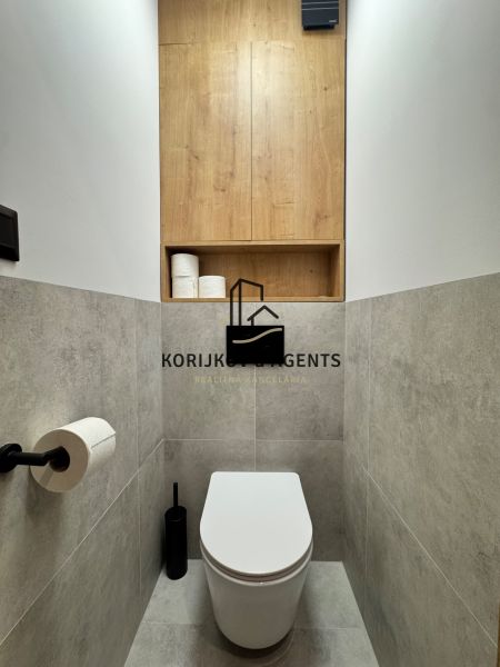 A toilet in a 3-room apartment with storage space and wood decor.