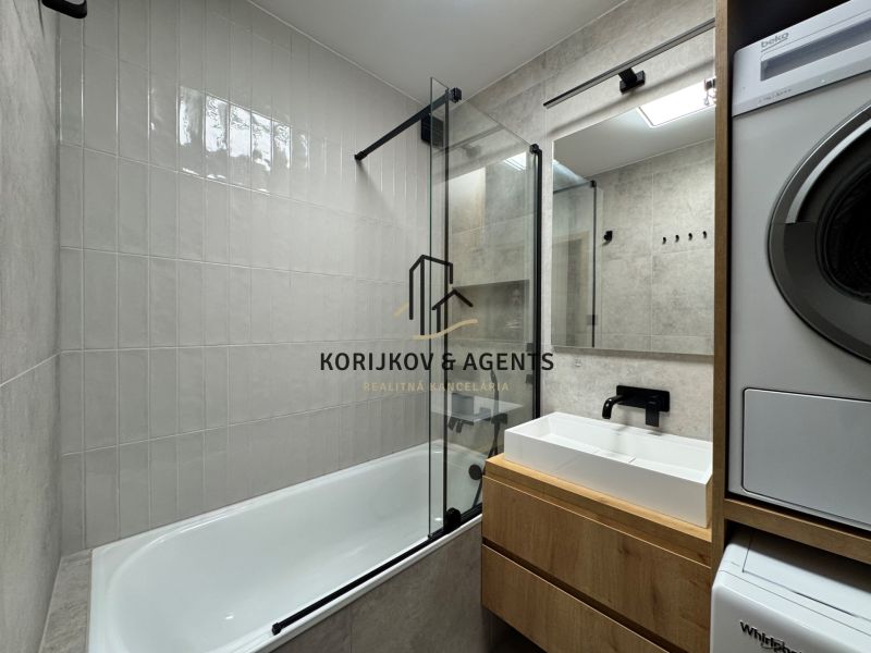 A modern bathroom in a 3-room apartment with a bathtub, sink, and washing machine.