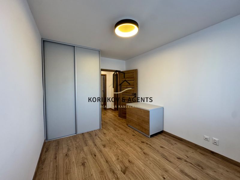 Bedroom in a 3-room apartment with a wooden decor floor and a built-in wardrobe.