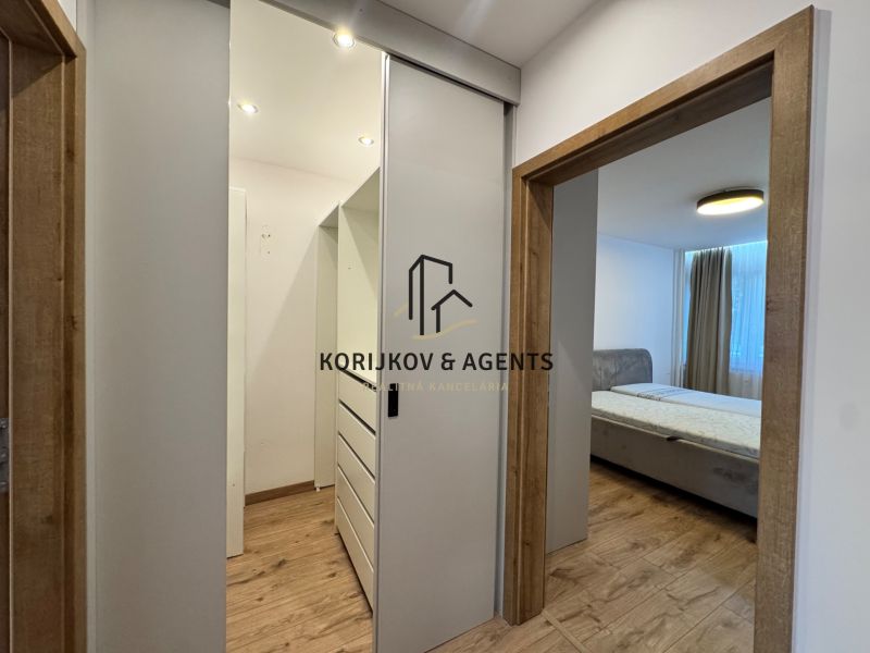 A hallway with sliding doors and a bed, a floor with a wooden decor in a 3-room apartment.