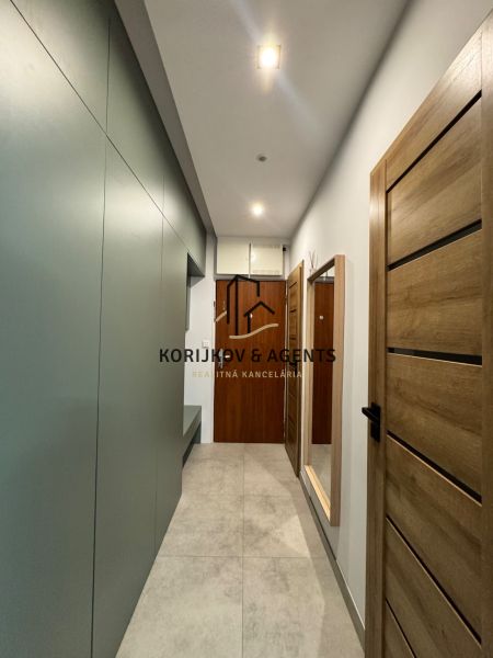 A hallway in a 3-room apartment with a floor and wooden doors.