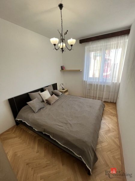A bedroom with a double bed and a wooden decor floor in a 3-room apartment.