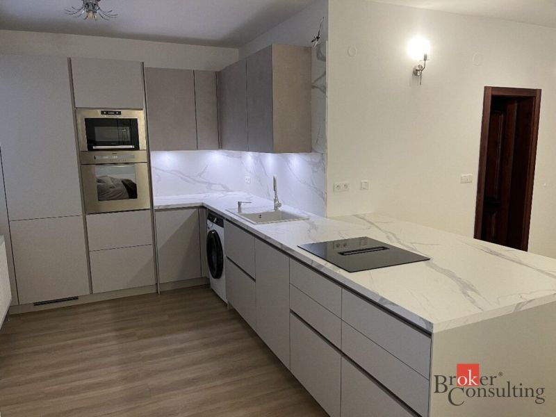 A kitchen in a 3-room apartment with a marble countertop and a floor with a wood decor.