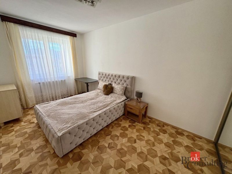 Bedroom with a bed, nightstand, and wooden-decor flooring, 3-room apartment.
