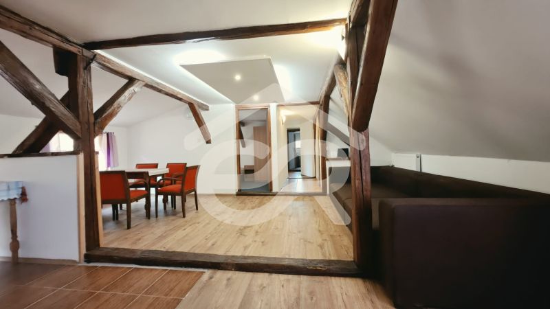 A recreational apartment with a wooden decor floor, wooden beams, and comfortable furniture.