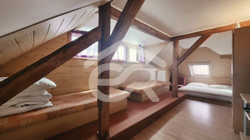 Attic room in a holiday apartment with a wooden decor floor and beds.