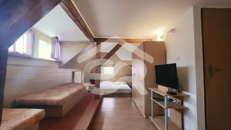 Interior of a holiday apartment with a bed, television, and wooden decor flooring.