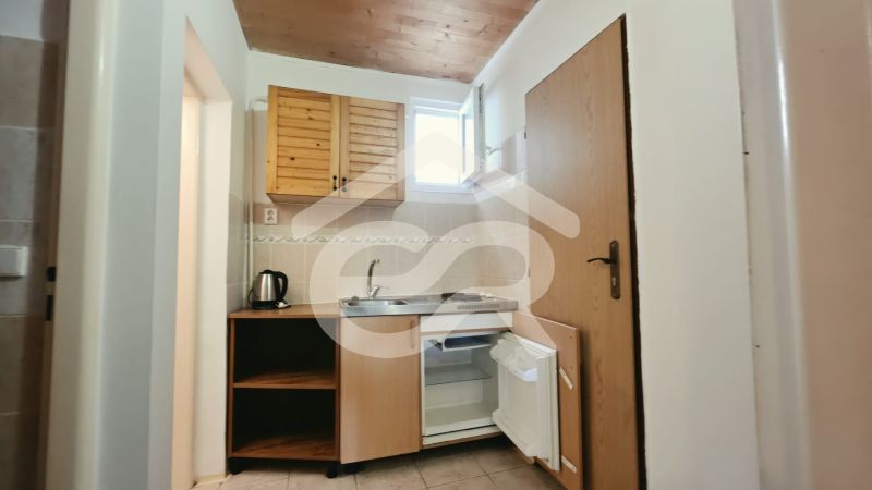 Kitchen corner in a holiday apartment with wooden cabinets, a sink, and a mini-fridge.