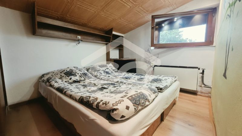 Attic bedroom with a double bed, shelf, and window, Holiday apartment.