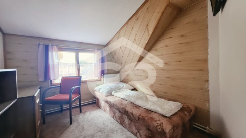 Single room in a holiday apartment with wood-patterned flooring and a window.