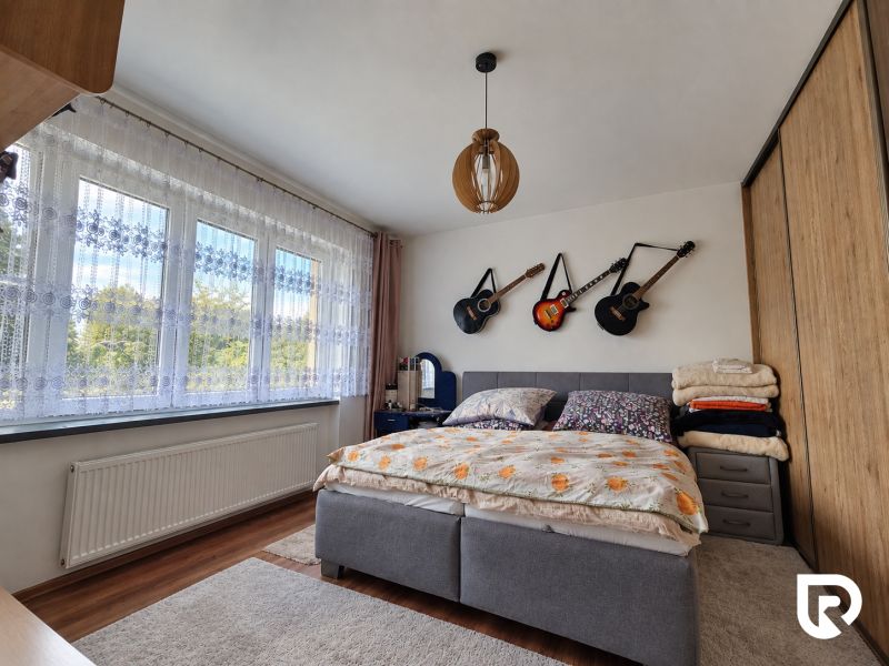 Bedroom in a family house with guitars on the wall, floor with wooden decor.
