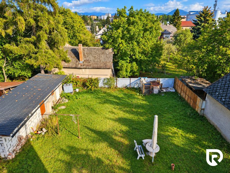 A garden of a family house in Martin with a lawn and visible roofs of nearby buildings.